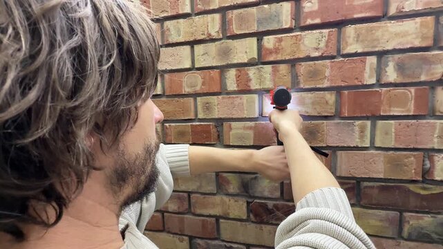 Man drilling into brick wall using power drill, construction and installation concept, creating hole in masonry surface