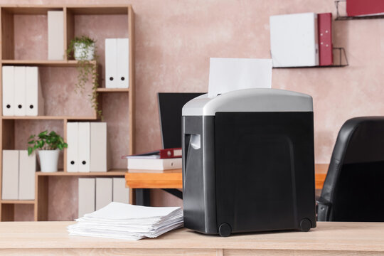 Shredder with documents on shelf in modern office