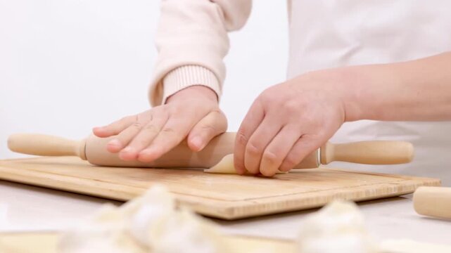 Unidentified hands elderly woman baker chef wear apron preparing dough flattening it with rolling pin for baking homemade pastry bakery food rolling dough on home kitchen table raw fresh ingredients