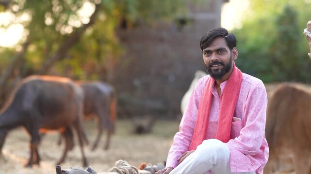 young indian farmer sitting with bull at indian rural village