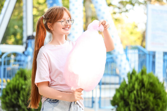 Teen girl eating cotton candy in amusement park
