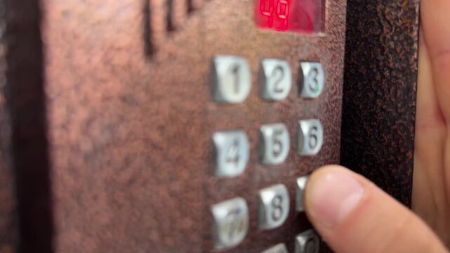 Person pressing button on door intercom keypad outdoors to open entrance door, access control action, security system use, everyday routine