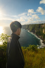 Fototapeta premium Man posing at Manta Point on Nusa Penida, Bali, enjoying tropical ocean landscape and adventure travel atmosphere.