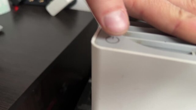 Person turning air purifier on and off with hand close up at home, controlling device operation, clean air technology use concept