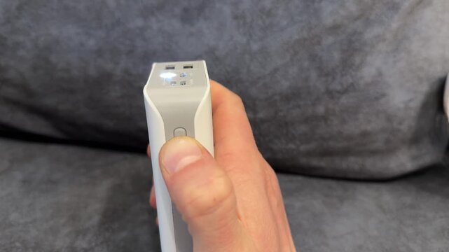 Hand pressing power button on portable device close up, switching small electronic gadget on or off concept