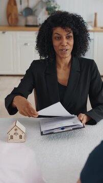 Business talks about real estate deal, aged spouses consultation with broker. Smiling african american lady discussing with clients conditions of agreements of mortgage or bank credit, shake hands
