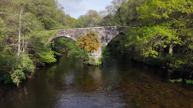Medieval Bridge Over Parga River Near The Capela de San Alberte In Guitiriz, Galicia, Spain. Aerial Ascending Shot