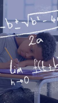 Vertical video: Male pupil writing with pencil leaning on arm when chalk math forming solving math