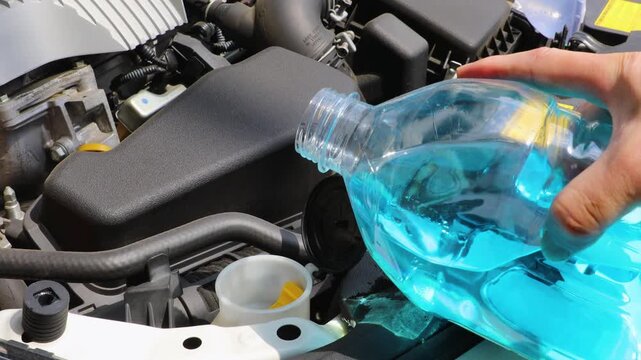 自動車のボンネットを開けてウィンドウォッシャー液を補充している
