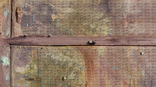 drone shot of solar farm construction showing trucks, mounting frames and earthworks across site