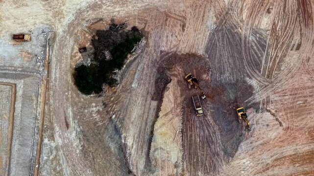 Aerial view of active mining site. Heavy machinery moves earth and rock daily. Workers operate equipment with focus and precision.