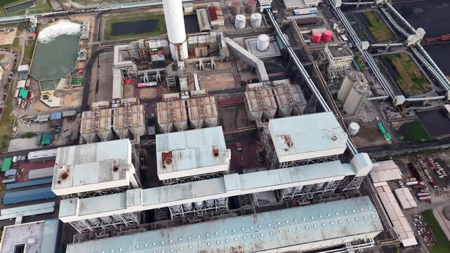 Drone aerial view of expansive industrial power plant with cooling stacks and conveyors.