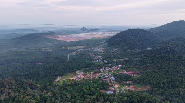 Drone aerial over rural datacenter and dense tropical forest with misty mountains and village roads.