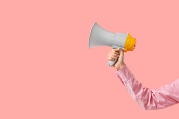 Fototapeta premium Female hand holding megaphone on pink background