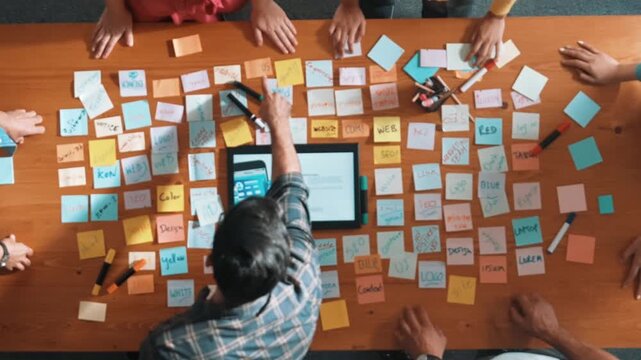 Aerial view of developer team discussing and showing digital program and writing by using Ux Ui design. Top down view of business people develop wireframe prototype for phone and computer. Symposium.