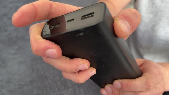 Hand trying to power on discharged power bank close up, empty external battery pack and charging problem concept