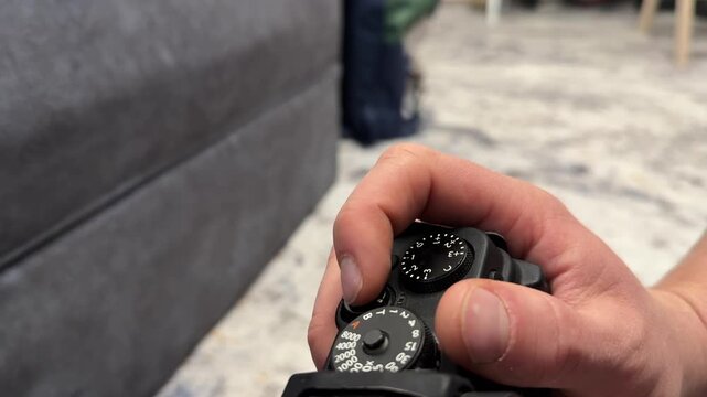 Hand rotating control dial on digital camera top panel, adjusting shooting settings and photography equipment concept