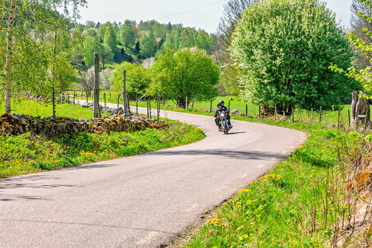 Motorcyclist on winding country road in lush spring landscape