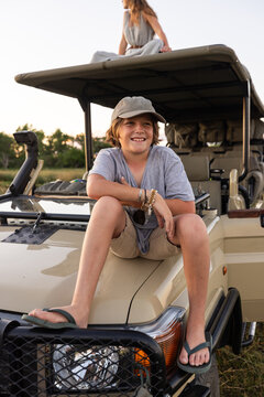 smiling young boy on hood of safari vehicle, Okavango Delta, Botswana, Africa