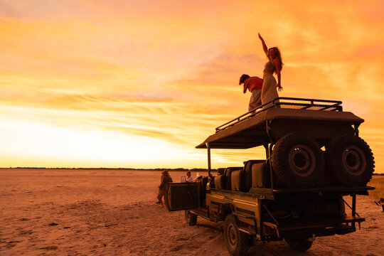 siblings atop safari vehicle at dusk, Makgadikgadi Park, Botswana, Africa