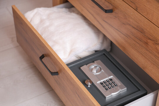 Open drawer with safe and plaid in room, closeup