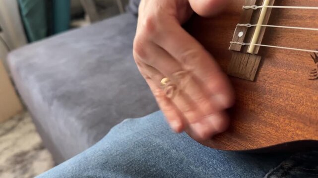 Person hitting acoustic guitar body with palm close up at home, producing strong rhythmic percussion sound, improvised music activity, creative hobby concept
