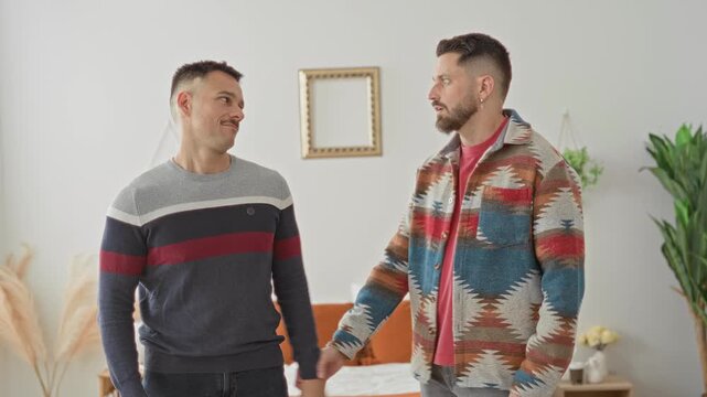 Man embraces partner on bed in studio, patterned jacket and striped sweater visible, arms around shoulders and back; intimacy support comfort.