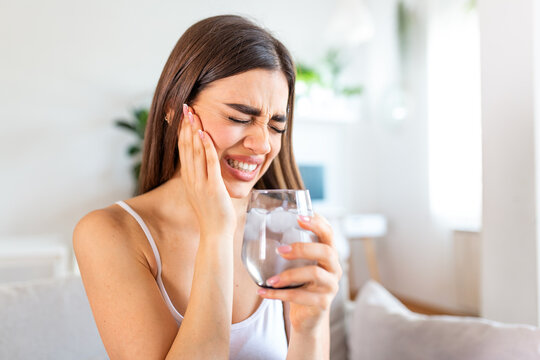 Tooth sensitivity. Dental problem, People with toothache problem, Healthcare And Medicine concept. Attractive woman holding glass of cold water with ice and touching painful cheek. Sensitive teeth.