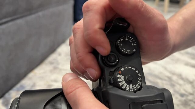Hand gripping digital camera and changing mode dial, photography equipment setup for shooting concept