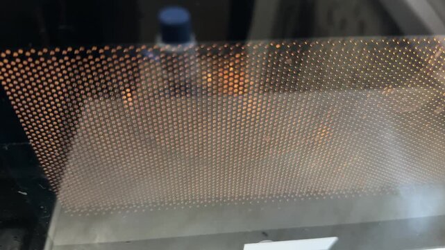 microwave oven door mesh window in close up, kitchen appliance front panel detail
