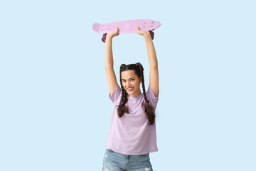 Beautiful young happy woman with braids holding skateboard on blue background © Pixel-Shot