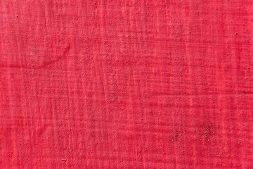 Fototapeta premium Textured red painted wall surface with rough matte industrial finish.