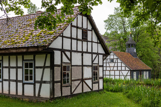 View of Hennebergisches Museum Kloster Vessra with traditional half-timbered buildings, moss-covered roofs, and lush green trees Kloster Vessra, Thuringen, Germany.