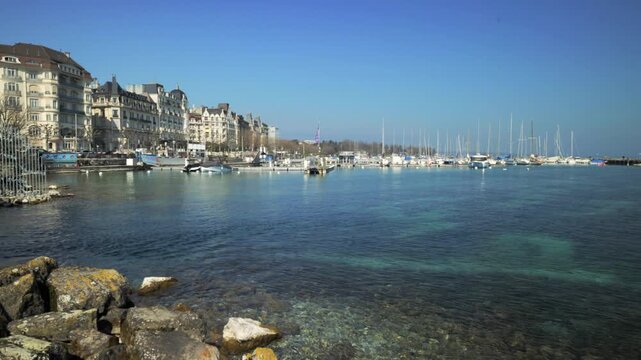 Panning shot of Lake Geneva harbor, waterfront buildings and boats