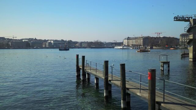 GENEVA, SWITZERLAND - MARCH 19, 2026: Panning shot of Lake Geneva with the wooden pier at Bains des Paquis