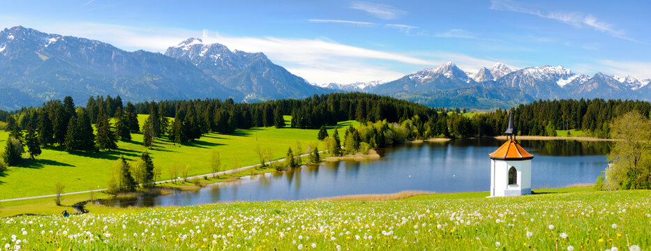 Panorama Landschaft im Allg&auml;u mit Fr&uuml;hlingswiesen und der Kapelle am Hegratsrieder See