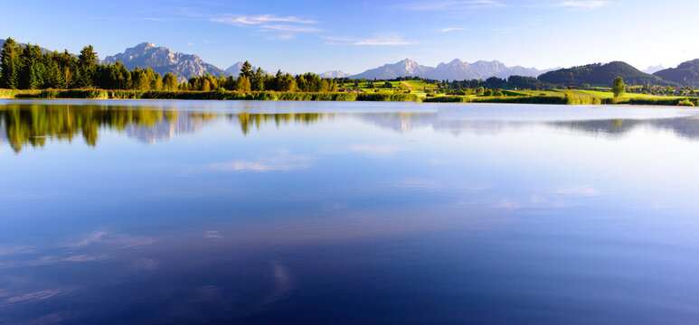 Im Allg&auml;u spiegeln sich die Berge auf der Wasseroberfl&auml;che des Huttler Weiher bei Ro&szlig;haupten