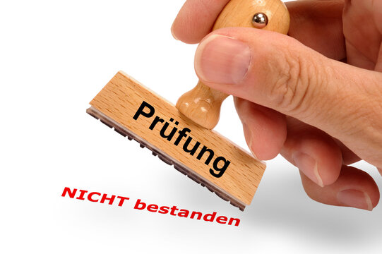 Eine Hand h&auml;lt einen Holzstempel mit dem Aufdruck  - Pr&uuml;fung NICHT bestanden