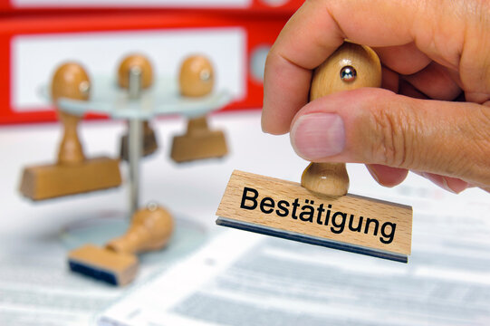 Ein Holzstempel mit Aufdruck Best&auml;tigung &uuml;ber Dokumenten