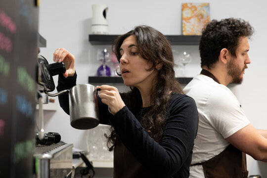 Barista steaming milk using an espresso machine, preparing a coffee drink