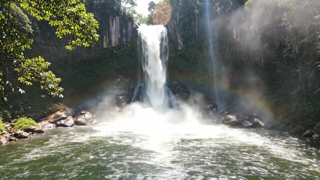 majestic waterfall plunging into clear pool, rainbow in mist, lush green jungle, tropical paradise, serene nature scene