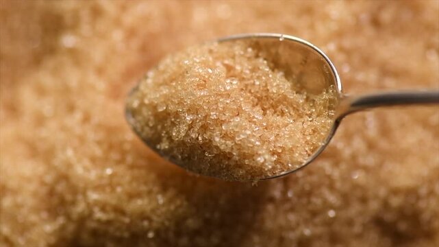 Brown Cane sugar in a spoon close up. Brown sugar background. Heathy eating, diet concept. Top view, flat lay, slow motion. Macro shot. 