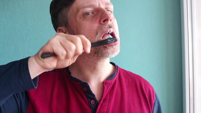 Adult man brushing teeth in home bathroom, daily hygiene routine, oral care and healthy lifestyle concept.