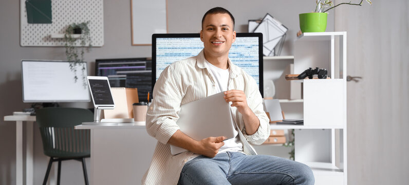 Handsome programmer with laptop sitting in office