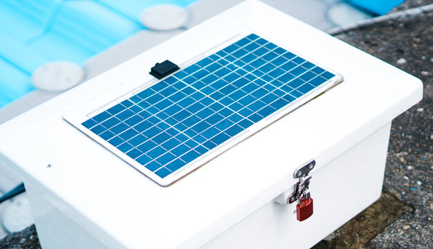 A white locked box with an integrated solar panel on top at a marina