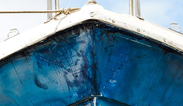 close up of a blue painted boat hull with scratches and dents