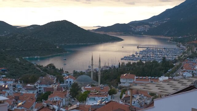 Kas marina reflecting golden hour light in calm waters. Golden hour sunlight reflects on the calm waters of kas marina, nestled amidst rolling hills and traditional turkish architecture