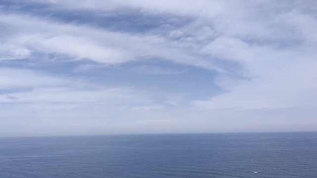 Mare calmo sotto un cielo parzialmente nuvoloso, con gabbiani in volo; scena naturale serena che trasmette libert&agrave; e ampiezza