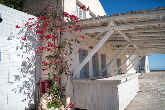 Traditional white seaside building with blooming bougainvillea near open-air theater in Paralio Astros Greece