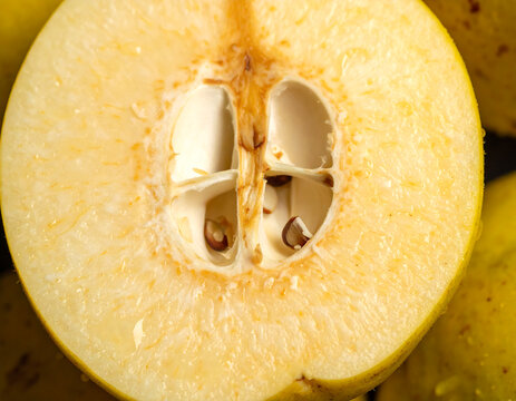 Macro illustration of a halved quince fruit revealing the core seeds and grainy golden flesh